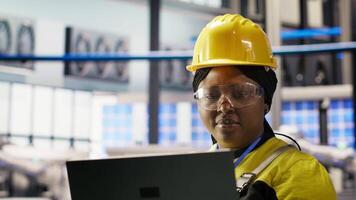 Specialist using laptop to conduct routine inspections in industry 4.0 plant producing renewable energy. Technician in photovoltaics smart factory testing equipment using notebook, camera B video
