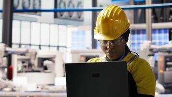 Portrait of smiling solar panels factory engineer analyzing data on laptop to predict gear failures. Happy photovoltaics plant employee using notebook, following maintenance procedures, camera B video