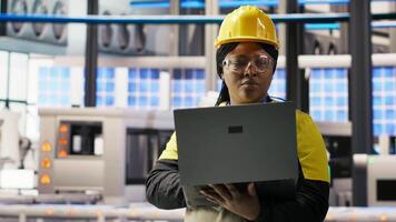Solar panels factory engineer analyzing data from IoT sensors to refine equipment operational efficiency. Worker performing system diagnostics to reduce downtime in photovoltaic production, camera B video