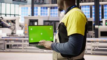 Factory engineer using green screen laptop to calibrate high tech machinery and analyze sensor data. Industrial plant employee uses chroma key notebook to troubleshoot assembly equipment, camera A video