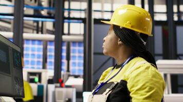 Woman in smart factory expert uses computer to implement automated workflows. African american technician using PC in industry 4.0 plant to integrate sensors into production, camera B video