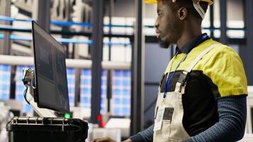 Solar panels plant engineer uses PC to oversee systems, ensuring machinery operates at optimal efficiency. Photovoltaics plant worker uses computer software to maintain continuous operations, camera B video