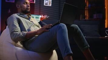 Black male freelancer taking online course to learn new skills from home, attend online call and watching lecture from loft. Young man participates at a virtual training class. Camera A. video