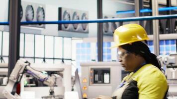 Industrial plant engineer using laptop to implement automated workflows and control systems, computerizing operations. African american technician integrates sensors into production using notebook video