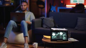 Black IT professional in loft working on cybersecurity with gadgets, tackling hacking attempts, encryption and cyber defense. Screen shows security breach warning, data security risks. Camera B. video