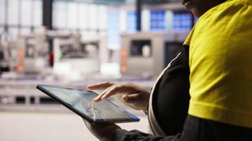 Close up of engineer in industry 4.0 plant designing robotic production lines using CAD application on tablet. Smart factory specialist uses software to optimize floor layouts, camera A video