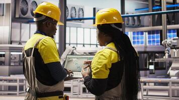 Smart solar panels factory engineering team using laptop to oversee production lines. Teamworking industry 4.0 plant coworkers ensure machinery operates at optimal efficiency using notebook, camera A video