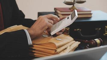 A man in a suit is using a calculator to calculate the amount of money he owes video