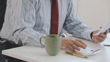 A man in a business suit is using a calculator and holding a piece of paper video