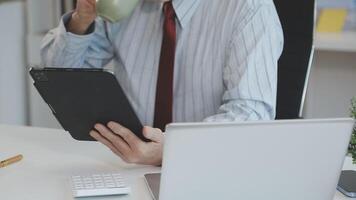 A man in a tie and glasses holding a tablet computer and talking on the phone video