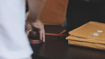 A judge's gavel is placed on a table with a brown envelope video