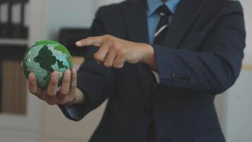 A man in a suit points to a globe video