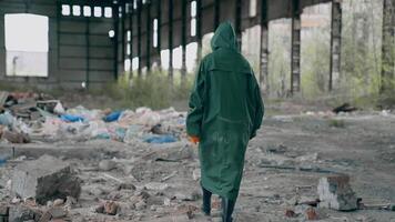 Person in abandoned place with garbage. Ecologist in protective suit walking inside the ruined building. Back view. Destructed place. video