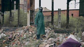 Survivor in destructed place. Human in protective clothing and respirator standing on a pile of garbage in abandoned place. High level of radiation. video
