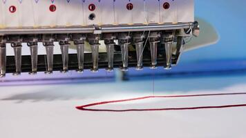 Automatic embroidery machine is working. Sewing machine needle in motion. Sewing machine needles with different colors moves up and down on white fabric. Close-up. video