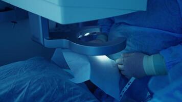 Eye surgery in the operating room. Eye-surgeon operating patient through laser vision correction machine. Close-up. Blue light. video