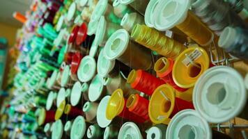 Spools of thread of different colors on the table. Collection of colorful threads for sewing industry. Background of many spools with cotton string. video