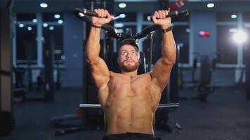 Training muscles. Sportsman pumping his trained body on a simulator. Strong trainer doing workout. Bodybuilder doing exercise on the modern simulator in the gym. video