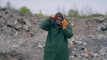 Ecologist puts on respirator in abandoned place. Man in protective suit protects himself with a gas mask in radioactive zone. Chemical attack. video