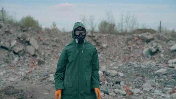 Man in safety suit and respirator on garbage background. Mad man in protective costume and gas mask dancing in abandoned place in radioactive zone. video