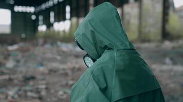 Human in radioactive territory. Person in a hazmat suit and gas mask walking in empty ruined building. Abandoned place after chemical attack. Rear view. video