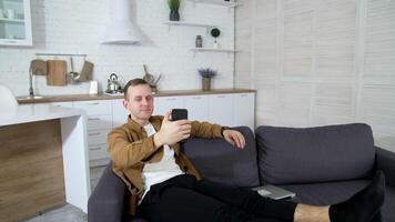 Young man using web camera. Guy doing call while sitting at home on sofa. Handsome male blogger doing a chat from his apartment. video