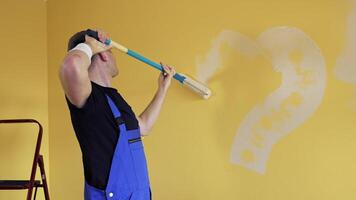 Man painting heart on a wall during makeover in flat. Painter improving the wall of a room with the roller on a long handle. Home repair. video