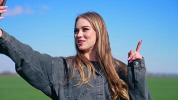 Beautiful female blogger speaking on camera outdoors. Happy young woman having a call on her phone in field. Sharing online activities. video