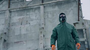 Human in protective costume and mask in infected place. Survivor man in a mask and a chemical protection suit showing on the camera with a finger. video