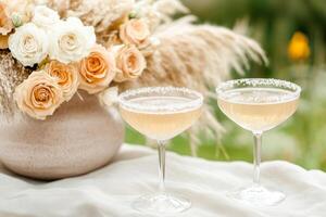 Sparkling coctails in a coupe glasses on an elegantly decorated table with a mix of roses and pampas grass photo