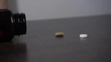 The patient accidentally knocked over a container of various medicines on the table, causing some of the pills to spill out. video