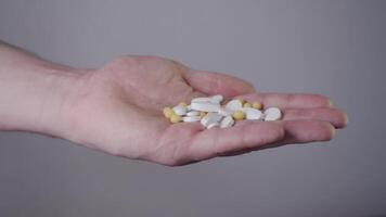 Man holds in his hand large number of different pills, all of which are incompatible with each other. dose is life-threatening. Close up. Studio shot. video