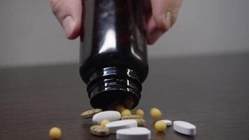 A multitude of diverse tablets are spilled onto the table from a container of medication. Slow motion. Close up. Studio shot. video