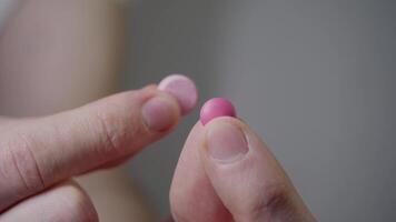 The patient is unable to decide between two different types of pink pills by holding them in his hands and examining them. Close up. video