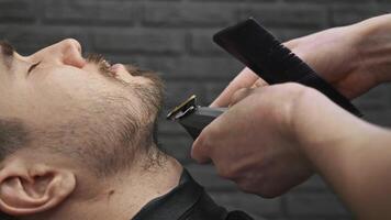 A close-up of face of customer at barbershop, as they are having their beard trimmed using a beard trimmer. video
