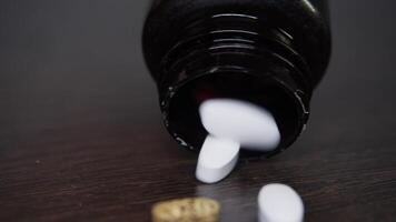 A large number of different pills are poured out onto the table from a medicine jar. Close up. video