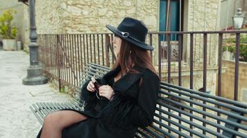 Elegant Woman In Black Coat Sitting On A Bench In Her Town And Looking Around video