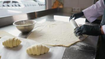 Baker rolls out dough for croissants on floured table video