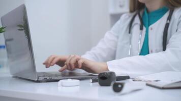 A doctor working on a laptop in a bright and organized office. Dressed in a white coat with a stethoscope around her neck, she focuses intently on the screen, reflecting professionalism and dedication video