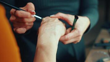 A makeup brush is gently tested on the hand to check its softness and precision. This step is part of a learning process for mastering beauty techniques video