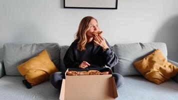Woman eats pizza and radiates joy, smile, closed eyes, soft laugh. Joy shines in every second, joy makes content relatable and rich in emotion. Pure delight on face as woman bites pizza. video