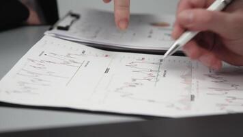 Two businessmen brainstorming with charts, papers, and a computer. Concept effective teamwork, strategy planning, and small business startup growth in an office environment video