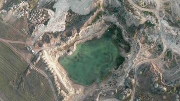 Aerial view of car by the edge of a flooded quarry. Drone footage of a small rock quarry flooded into a small lake. Aerial view of open cast mine. Turquoise background of the water in open pit. video