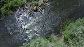 Aerial view of rocks across a section of a flowing stream. Trees and large stone boulders around. video
