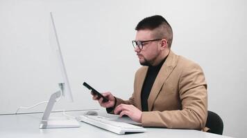 A businessman, call center manager, or entrepreneur consults a client on the phone in a bright office at a computer. The concept is remote work, effective consulting, and client support video