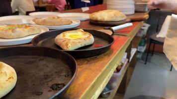 Cook arranging freshly baked Adjarian khachapuri with suluguni cheese straight from the oven plates video