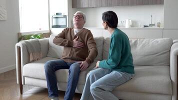 Senior man with chest pain, terrified wife unbuttons collar. Sudden heart distress panic anxiety video