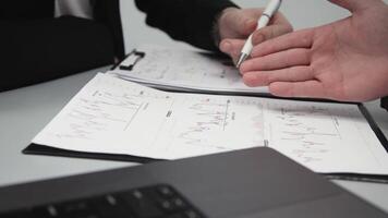 Two businessmen brainstorming with charts, papers, and a computer. Concept effective teamwork, strategy planning, and small business startup video