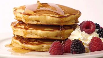 stacks of pancakes with berries and pour with honey sauce. video