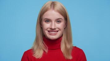 Smiling woman in red turtleneck on blue background video